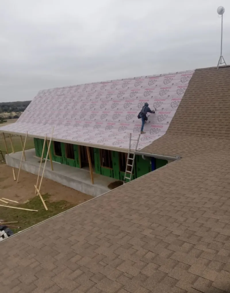 Worker preparing underlayment for a metal roof installation in Green Bay